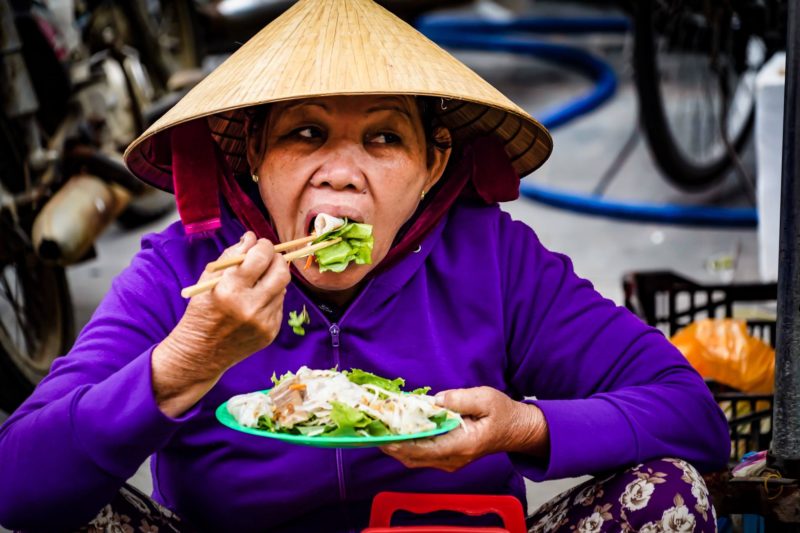 VIetnamese lady eating noodles in street market